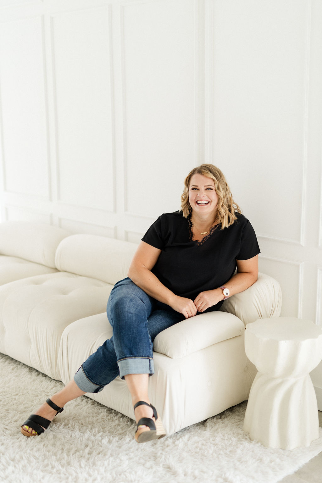 Photo of Lynn Marie Debilzen, founder of The Collective Shift Co., smiling and seated at a white picnic table outside with a laptop