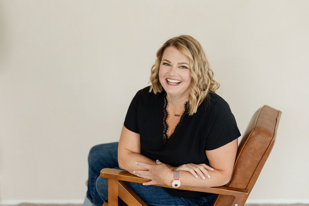 Photo of Lynn Marie Debilzen, founder of The Collective Shift Co., smiling and standing in front of blue wavy wall